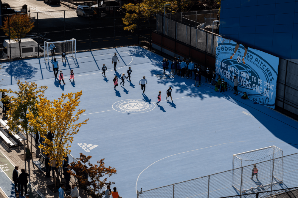 Aerial view of children playing soccer on a blue mini-pitch